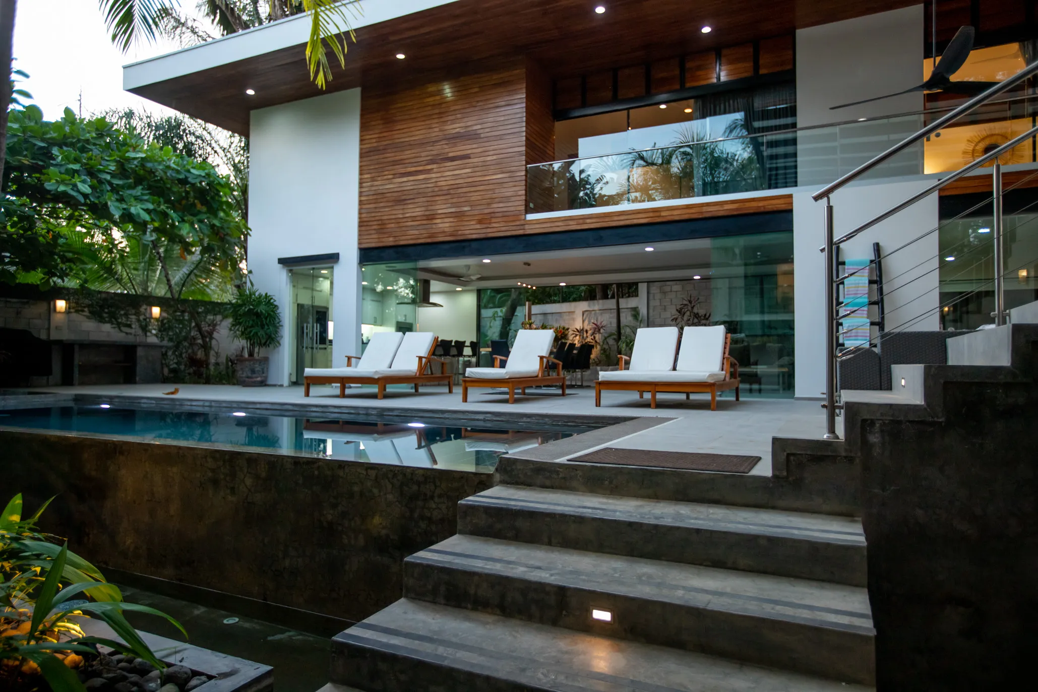 Casa Almendra villa pool terrace with sun loungers and wood-and-glass facade, South Playa Guiones, Nosara, Costa Rica