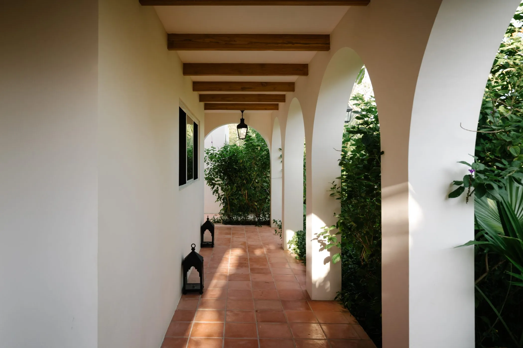 Casa Oceanus villa covered hallway with terracotta floor and arched openings, Nosara