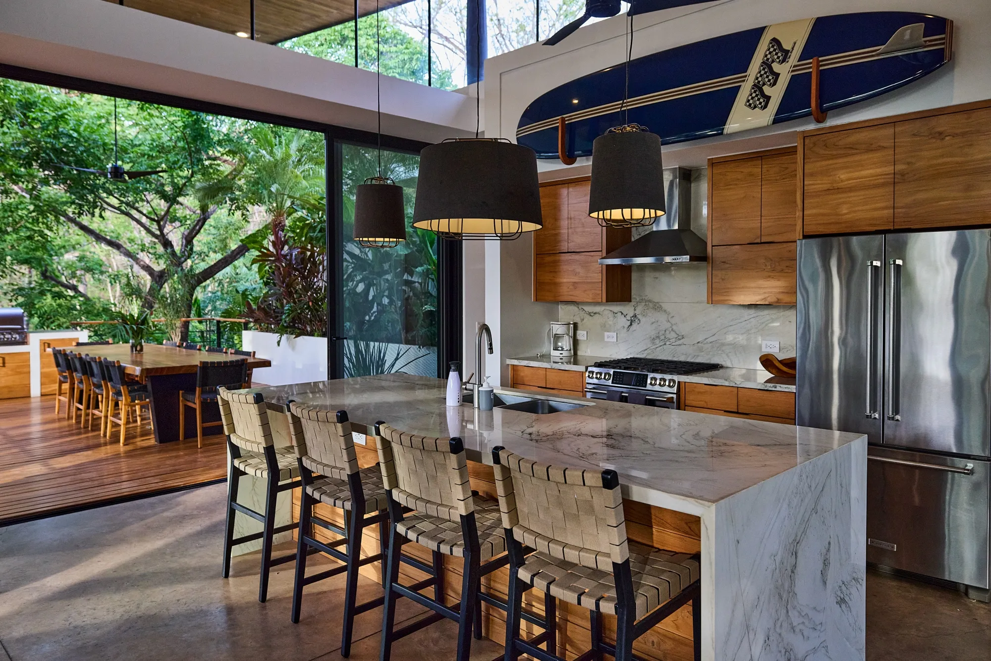 Terrace House villa kitchen bar with stools and surfboard accent, Nosara