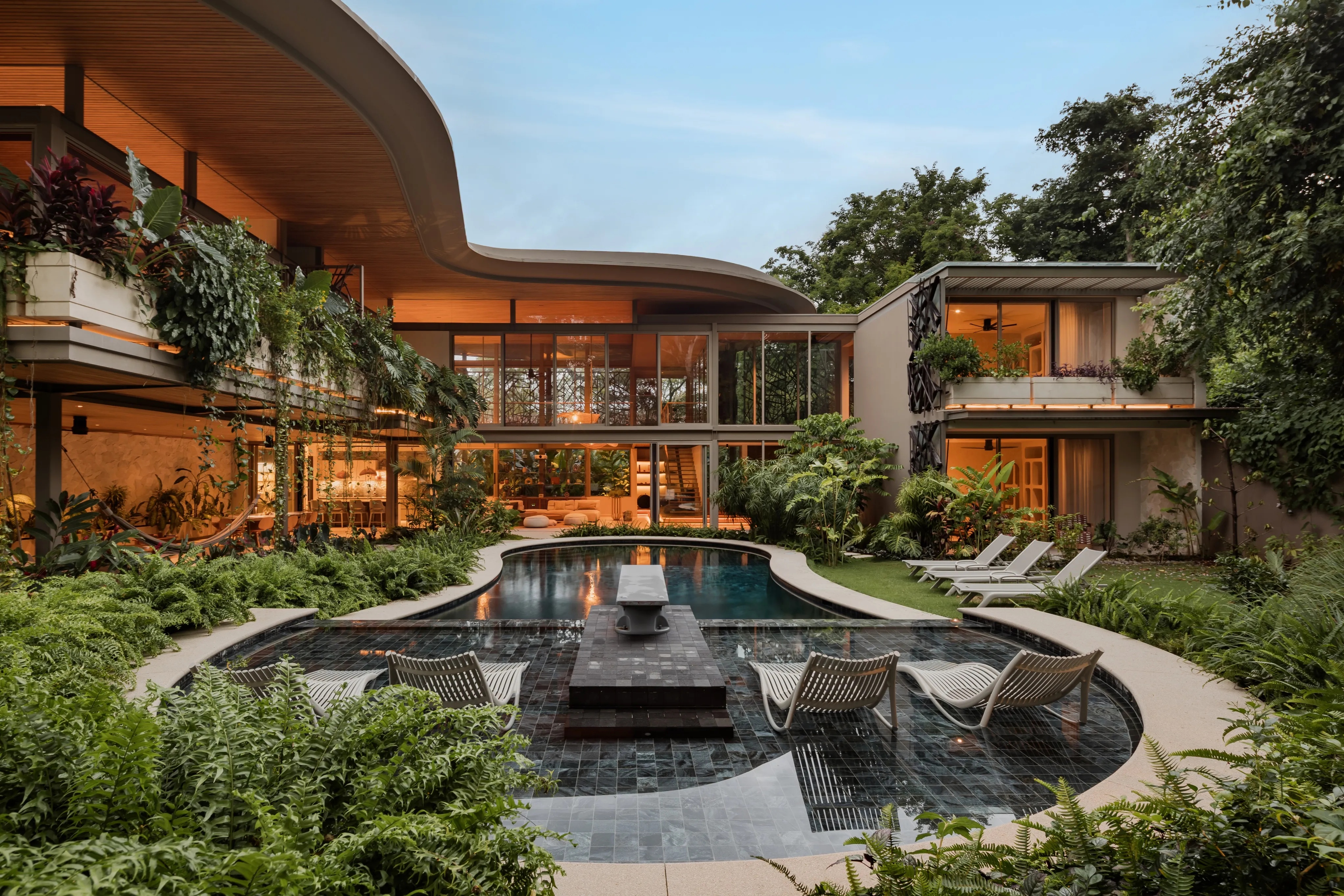 SEN villa exterior at twilight with curved roof lit above the pool, Nosara contemporary architecture
