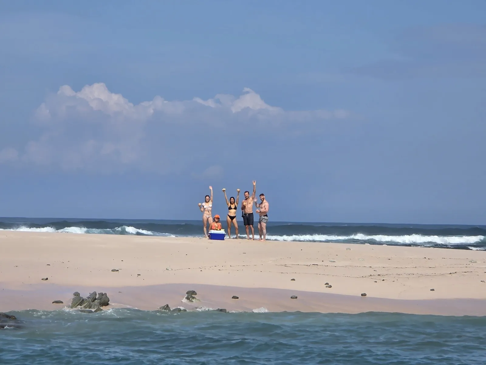 The group waving from a deserted sandbar reached by boat near Nosara