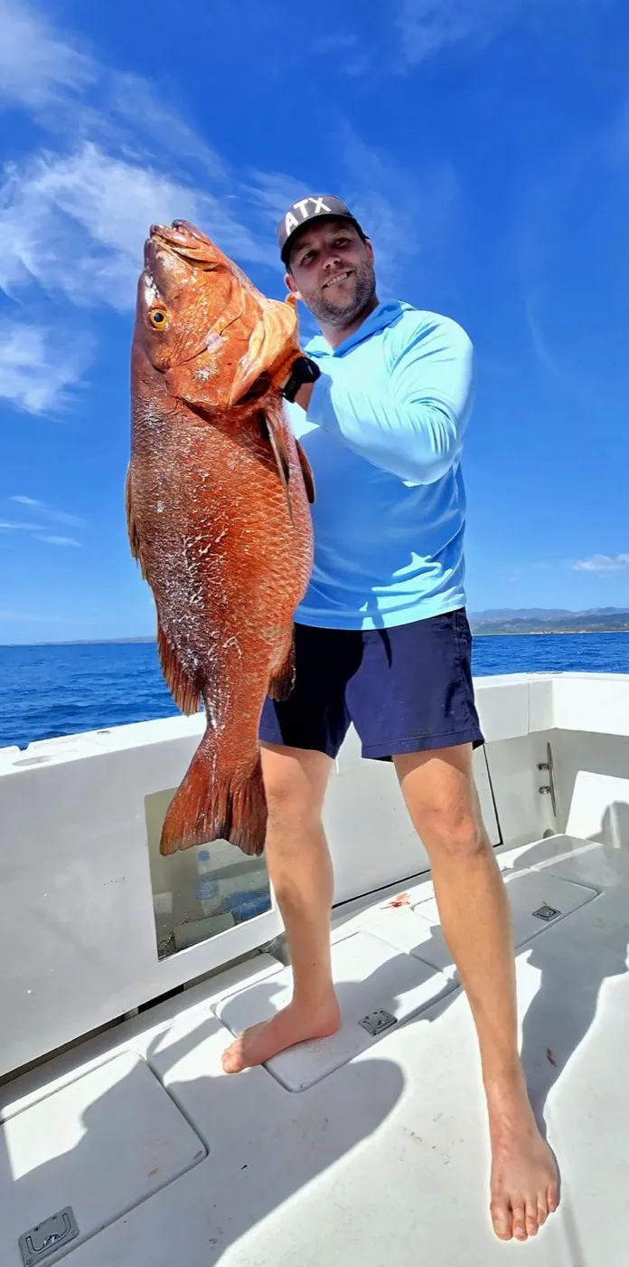 Angler holding a large snapper aboard the Osprey off Nosara